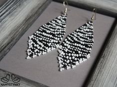 black and white beaded triangle earrings sitting on top of a piece of gray wood