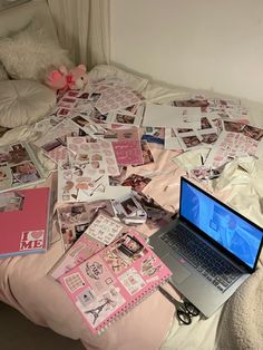 an open laptop computer sitting on top of a bed covered in pink and white stickers