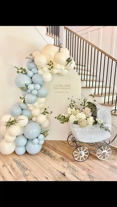 a baby carriage with balloons and flowers on the floor in front of a stair case