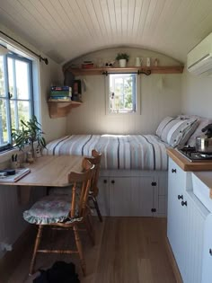 a small kitchen and dining area in a tiny home with wood floors, white walls and ceiling