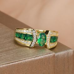 The 4x6mm emerald-cut green stone is beautifully set in a 925 silver band with a luxurious gold plating, offering a perfect blend of elegance and modern sophistication.Whether you're looking for a sophisticated accessory for a special occasion or a chic everyday piece, this ring delivers timeless beauty and fashion-forward appeal. The minimalist design highlights the vibrant green gemstone, which catches the light beautifully and adds a touch of glamour to any outfit. ✰ Crafted from high-quality Oval Green Emerald Ring With Gemstone Accents, Oval Cubic Zirconia Emerald Birthstone Ring, Green Cubic Zirconia Oval Rings, Green Gemstone Ring, Ring Elegant, Cubic Zirconia Jewelry, Ring Oval, Green Gemstones, Vibrant Green