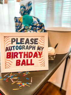 a birthday ball sign sitting on top of a table next to a stuffed animal in the background