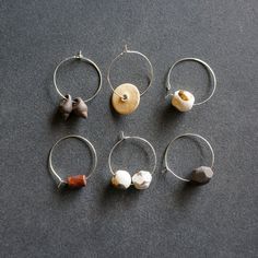 six pairs of silver hoop earrings with different shapes and sizes, all on a black surface