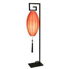 a lamp that is on top of a black stand with a red lantern hanging from it's side