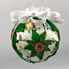 a christmas ornament hanging from a white string and decorated with colorful fabric flowers