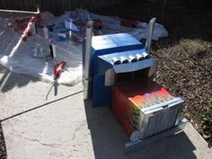 a cardboard box sitting on top of a cement slab next to a fence and trees