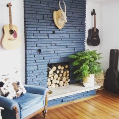 a living room filled with furniture and a guitar hanging on the wall above a fire place