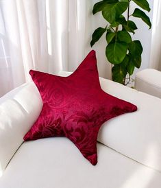 a red star pillow sitting on top of a white couch next to a potted plant