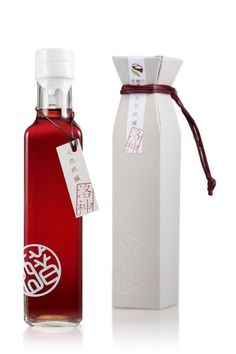 an empty bottle with a tag on it next to a white box and red string