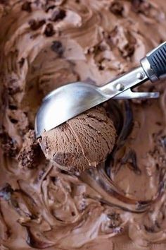 a scoop of chocolate ice cream on top of a spoon with a spatula in it