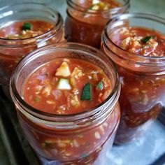 four mason jars filled with different types of food and garnish on top of a metal tray