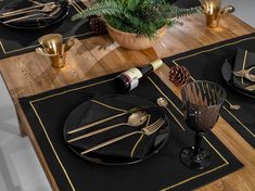 the table is set with black and gold placemats, silverware, pine cones, and wine bottles