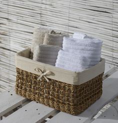 a basket filled with white towels sitting on top of a wooden bench