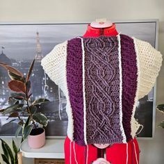 a purple and white knitted sweater hanging on a mannequin's back