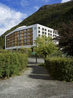 a large building sitting on the side of a lush green hillside next to trees and bushes