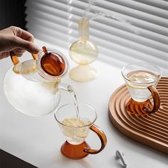 a person pouring tea into two glasses