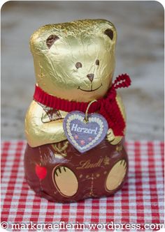 a chocolate bear sitting on top of a red and white checkered tablecloth with a heart