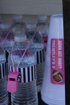 there are many water bottles with pink tags on them and one has a football in it