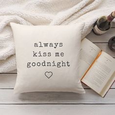 a pillow that says, always kiss me goodnight on it next to an open book