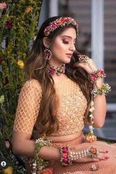 a woman sitting on the ground wearing a dress and jewelry