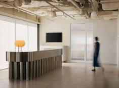 a person walking in an office building with a large counter and television on the wall