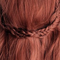 a woman with long red hair is braiding her hair