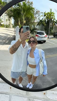 a man and woman taking a selfie in front of a mirror on the street