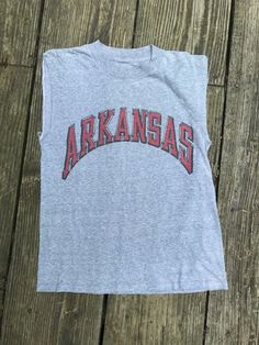 This is a great vintage School T Shirt. Nice gathered gray cotton or cotton blend. Cut off sleeves. No tags remain.   Condition-is good Measurements Lying flat unstretched: chest 18” Length bottom of back collar to hem 23” Retro Cotton Muscle Tee With Graphic Print, Vintage Cotton Muscle Tee With Graphic Print, Vintage Graphic Print Muscle Tee With Crew Neck, Vintage Cotton Muscle Tee With Crew Neck, Vintage Cotton Crew Neck Muscle Tee, Retro Crew Neck Muscle Tee With Graphic Print, Retro Muscle Tee With Graphic Print And Crew Neck, Vintage College Tops With Letter Print, Retro Graphic Print Muscle Tee With Crew Neck