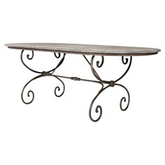 an iron table with a marble top and scroll design on the bottom, against a white background