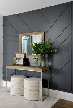 a console table with two stools and a mirror on the wall in front of it