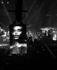 a black and white photo of a man in front of a cityscape at night