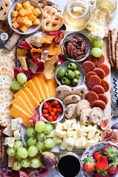 an assortment of cheeses, crackers and fruit on a platter