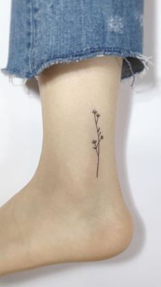 a small flower tattoo on the ankle that is sitting on someone's leg,