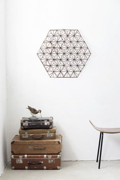 three suitcases stacked on top of each other in front of a white wall with a metal hexagonal sculpture