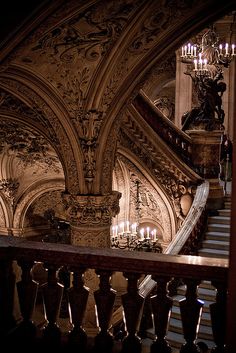 an ornate stair case with chandeliers and candles on the railing in front of it