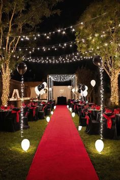 an outdoor event with red carpet, black tables and white balloons on the grass at night