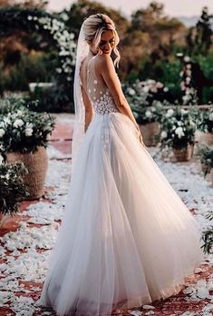 a woman in a wedding dress is walking down the aisle with flowers all around her