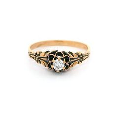 an antique style ring with a flower design and a single diamond in the center, on a white background