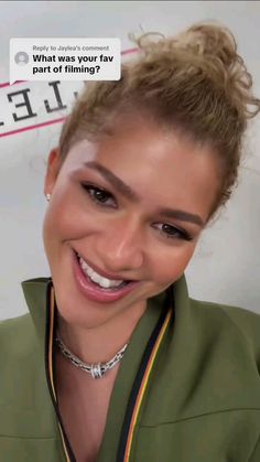 a woman smiling and wearing a green jacket with a white smile on it's face