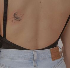 the back of a woman's stomach with a small tattoo on her left side