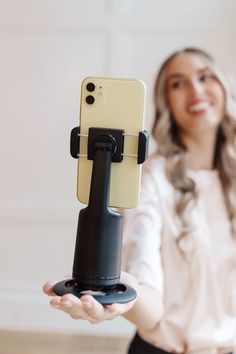 a woman holding up a cell phone in her hand with a holder attached to it