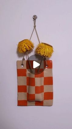 an orange and white checkered bag with two yellow pom - poms hanging from it