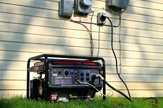 an electric generator sitting in the grass next to two power meters on a house's side