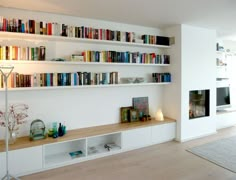 a living room filled with lots of books on top of white shelving unit units