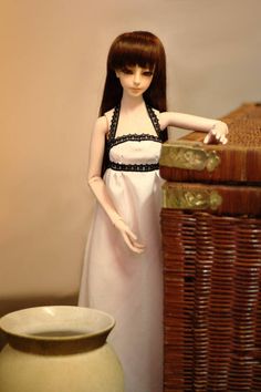 a doll standing next to a wicker chest