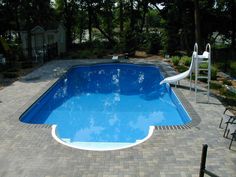 an empty swimming pool in the middle of a backyard with chairs and tables around it