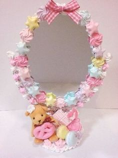 a teddy bear sitting in front of a mirror with pink and blue flowers around it