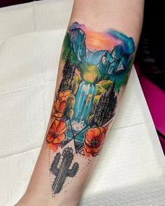 a person with a tattoo on their arm that has a waterfall and mountains in the background