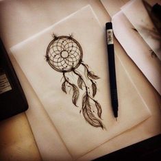 a drawing of a dream catcher on paper next to a pen