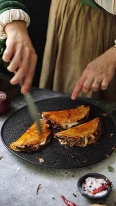 a person cutting food on top of a black plate